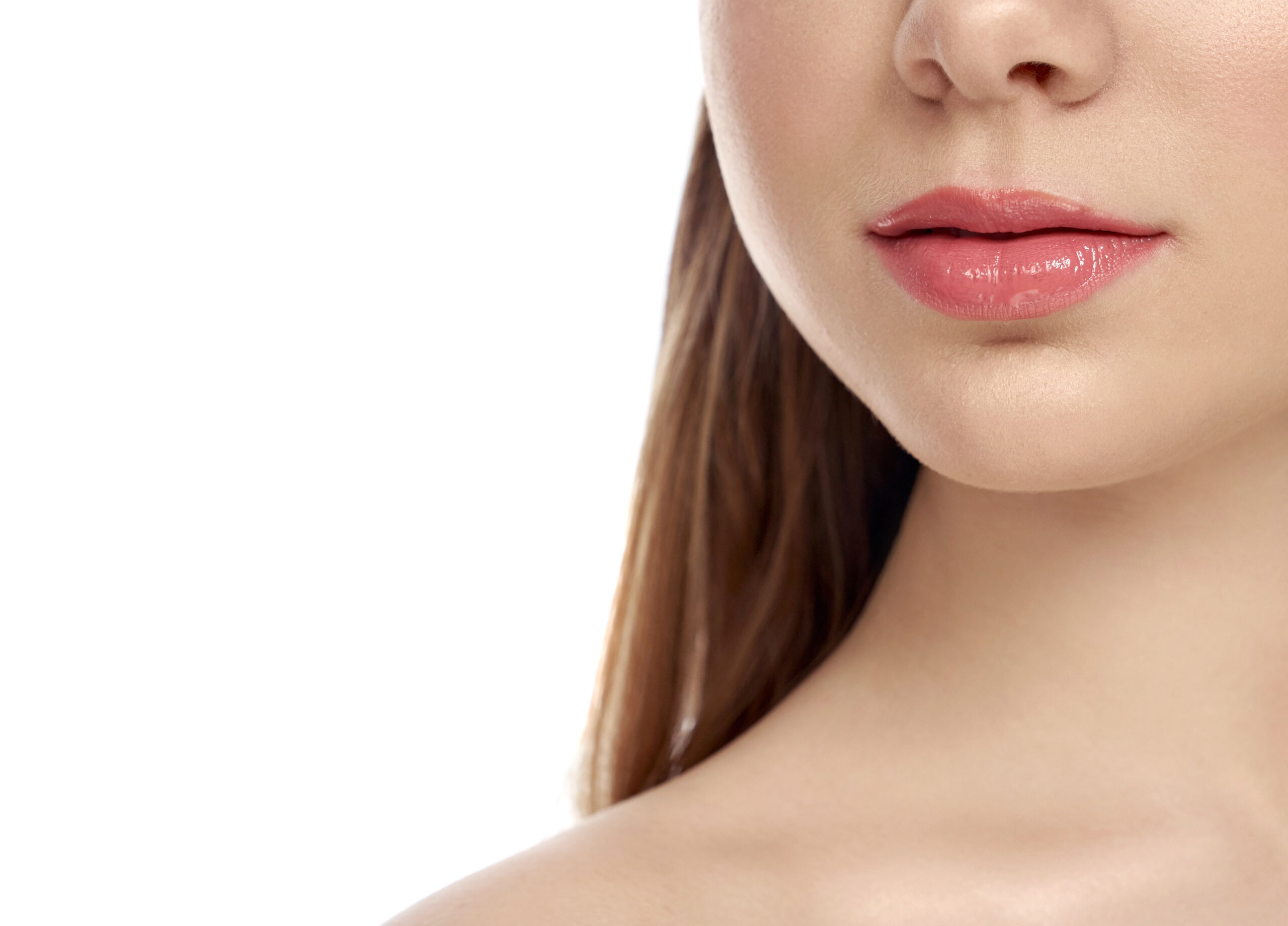 Selective focus of female full lips on isolated background Selective focus of female full lips on white isolated background. Young woman applying lip gloss and posing in studio. Lady with clean skin after beauty salon. Concept of face care.