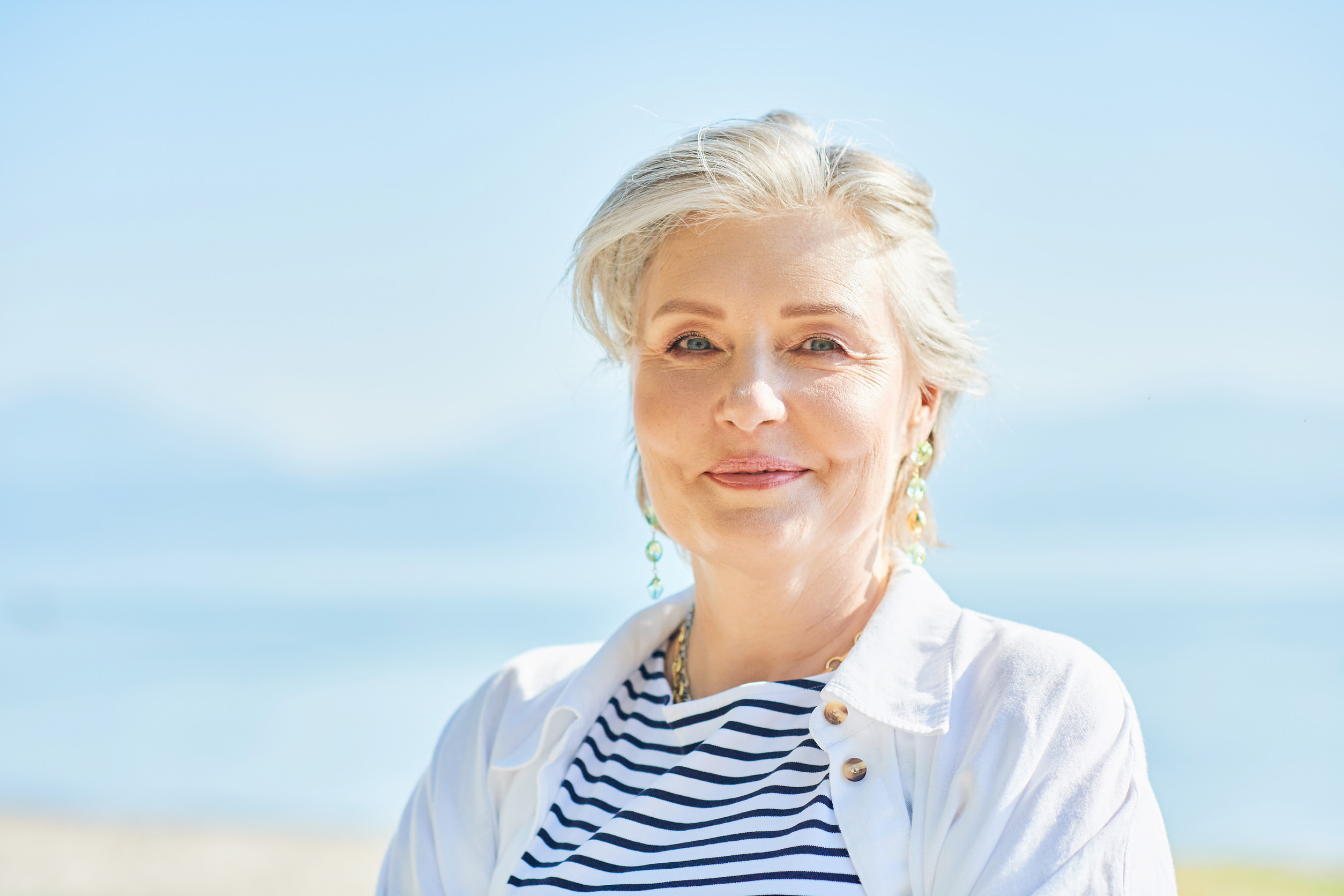 Outdoor summer closeup portrait of happy and healthy mature 50 - 55 year old woman enjoying nice sunny day by the lake or sea, active lifestyle Outdoor summer closeup portrait of happy and healthy mature 50 - 55 year old woman enjoying nice sunny day by the lake or sea, active lifestyle